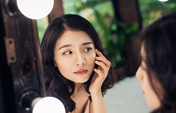 Young asian woman looking at the mirror.