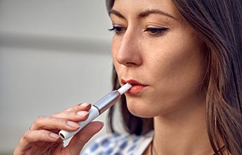 Close-up of a girl smoking an electric hybrid cigarette.