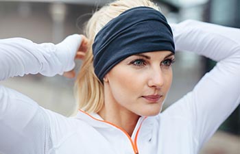 Close-up of young female athlete tying up hair before a run.