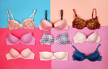 Set of different bras on multicolored background, top view.