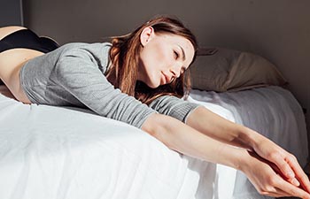 Brunette woman in underwear lies on the bed.