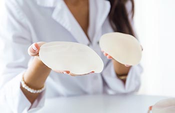 Portrait of female doctor choosing mammary prosthesis in the office.