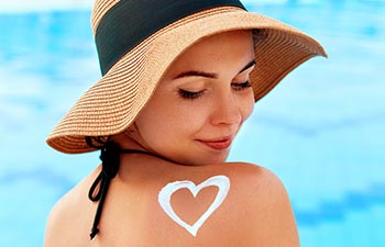 Woman applying sun cream creme on tanned shoulder.