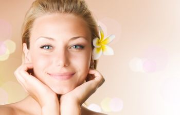 Smiling youthful looking woman with a flower in her hair.